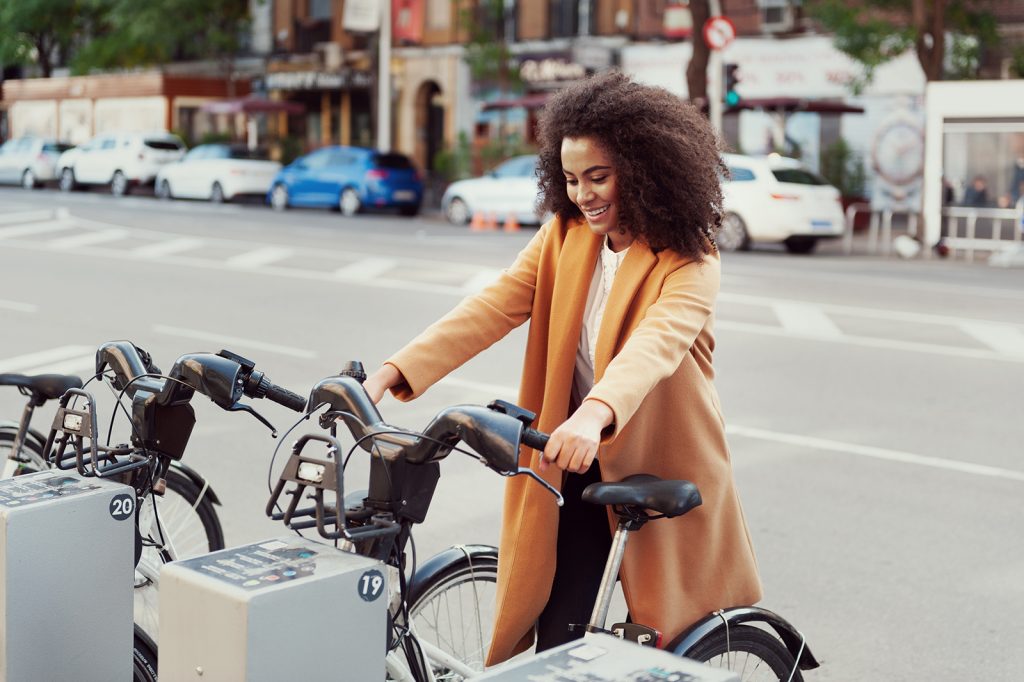 woman in urban station with electric bicycles for rent