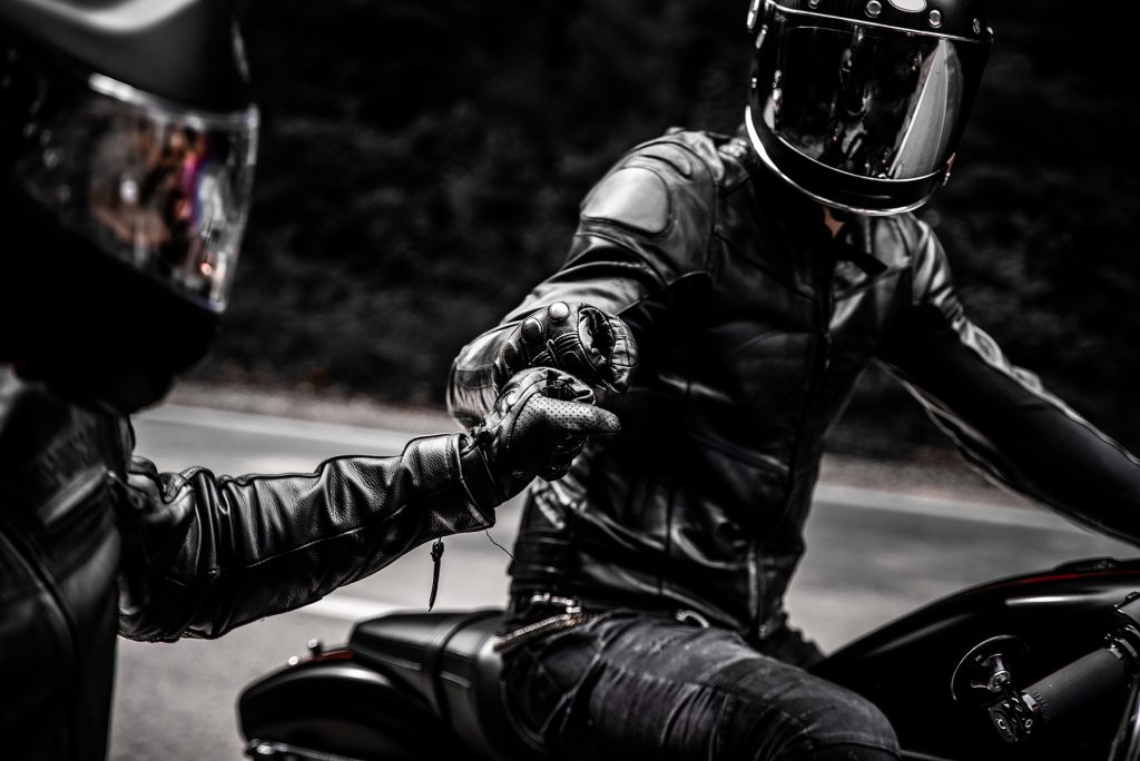 fist bump greeting of two motorbike riders in leather clothes and helmets