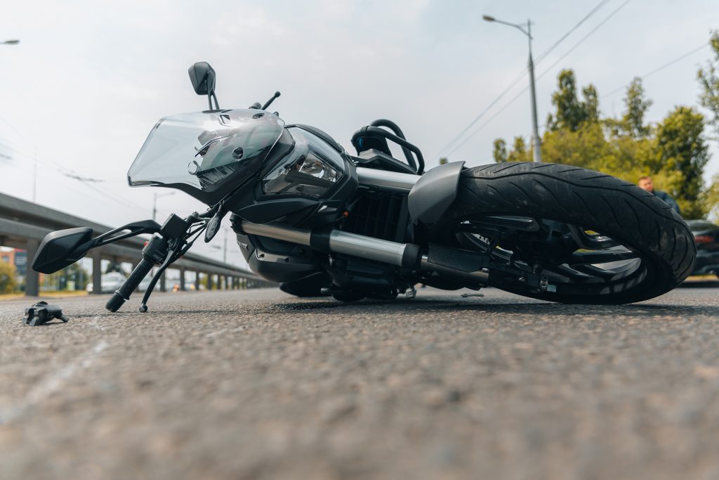 The motorcycle lies on the sidewalk after a ride. Serious accident. Accident, close-up. Lost control and fell. Driving hazards. Collisions with another vehicle.